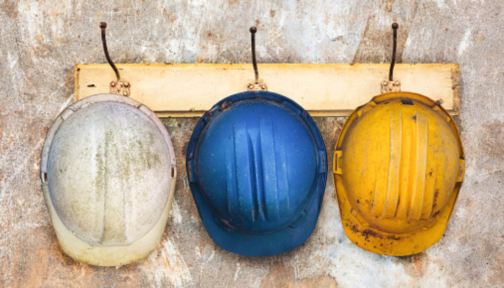 Three construction helmets hanging on an old wooden hat-rack