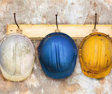 Three construction helmets hanging on an old wooden hat-rack